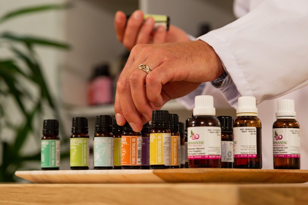Person arranging essential oil bottles on tray