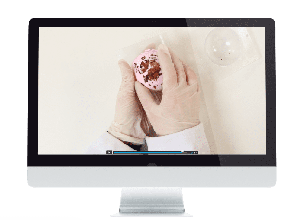 Gloved hands holding a pink soap bar.