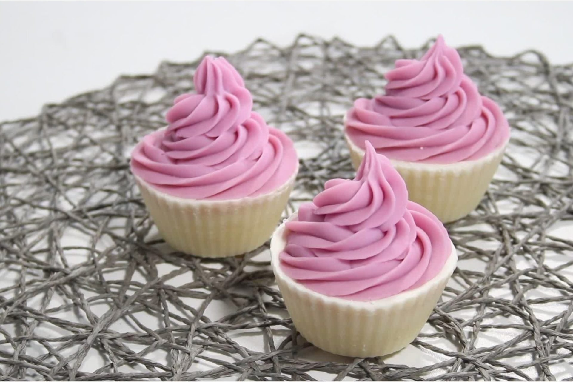 Cupcake soap Three cupcakes with pink frosting on decorative mat.